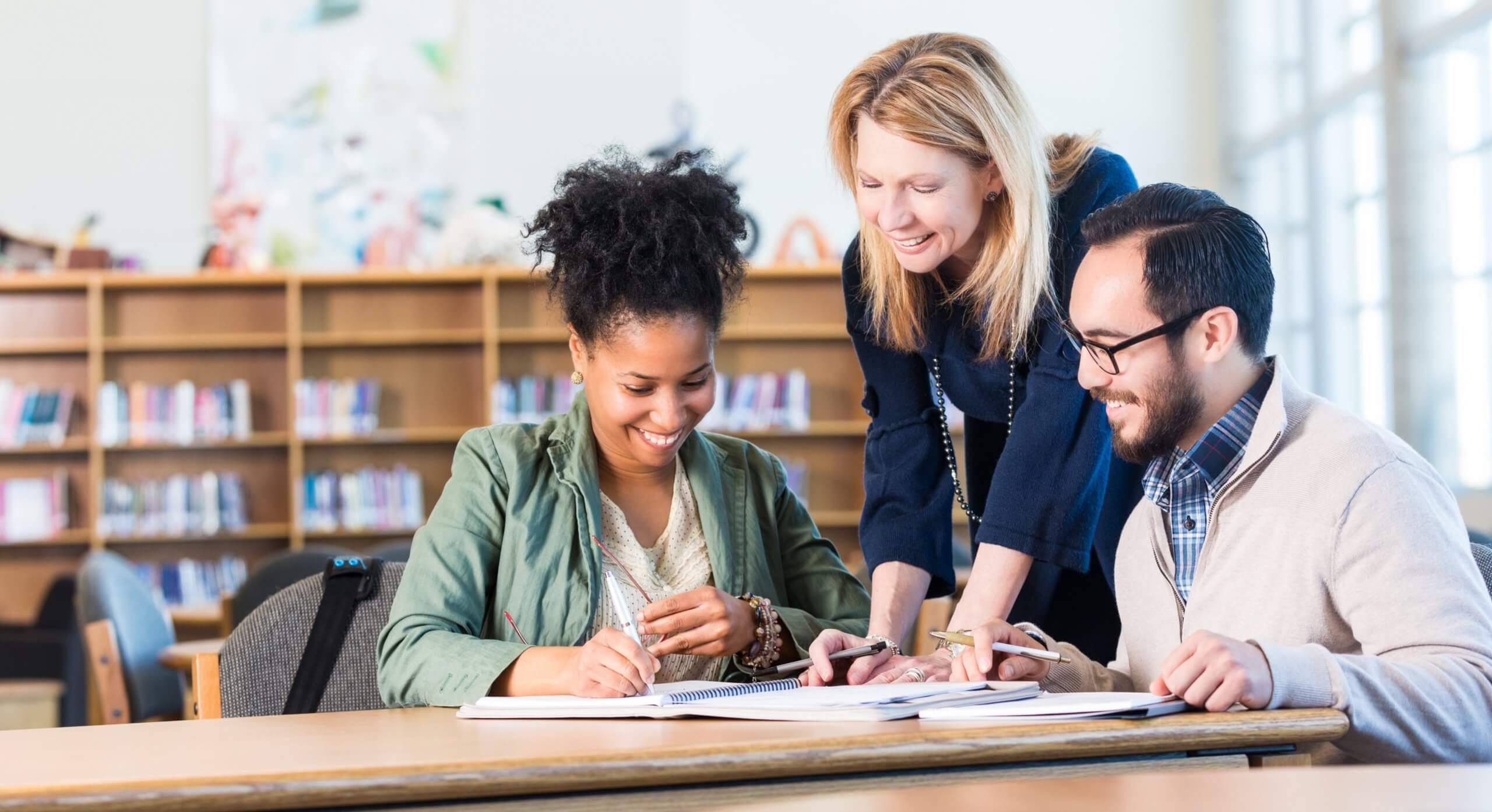 Three people discuss something at a library.