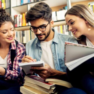 Three people happily discuss something at a library.
