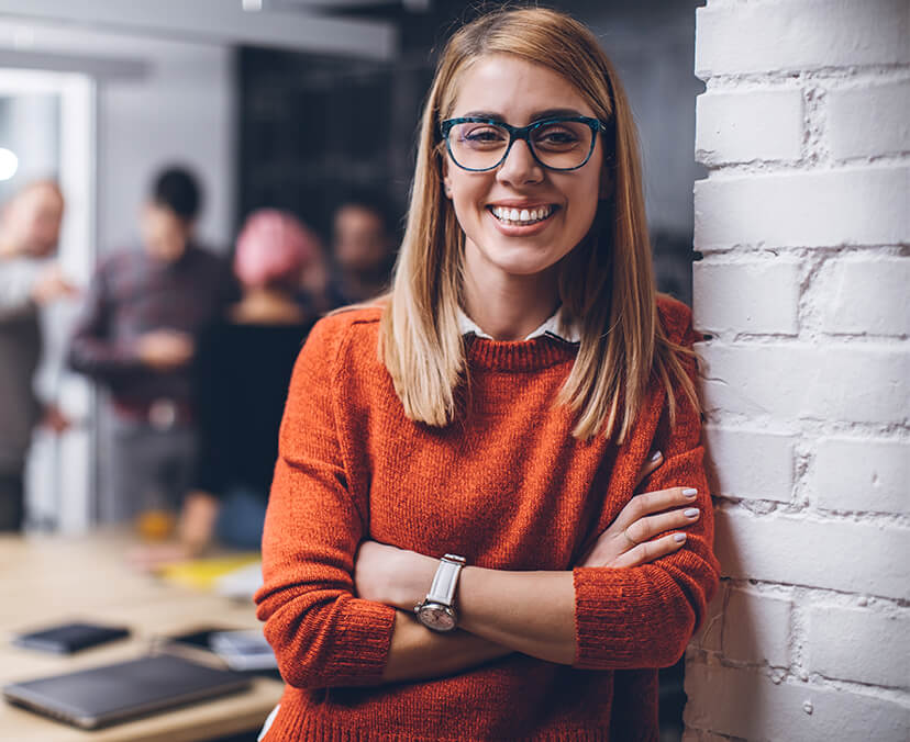 A woman leaning against a wall and smiling.
