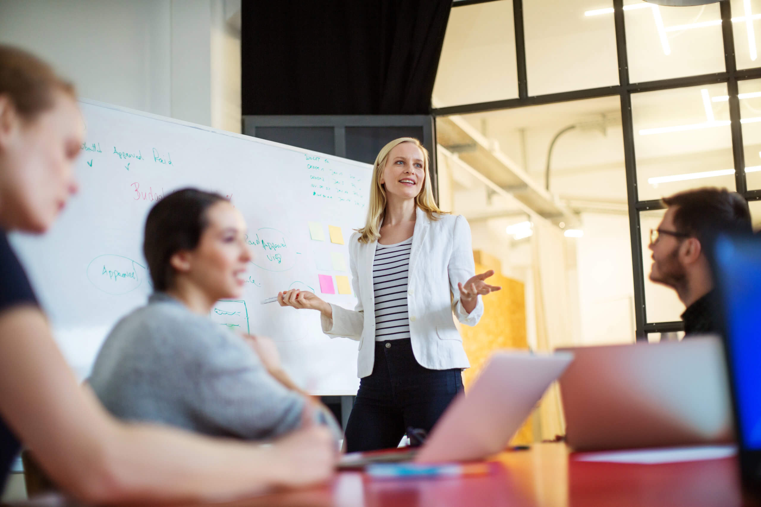 A woman leading a discussion with notes on a whiteboard.