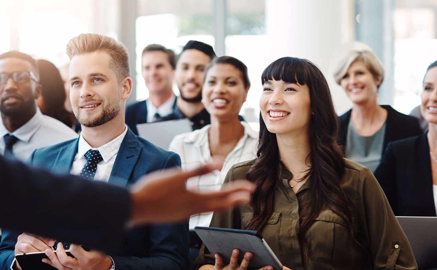 Diverse group of people sitting in a lecture, smiling.