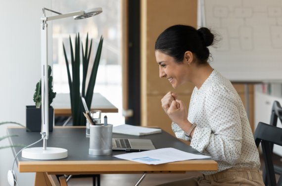 Student in front of laptop looking happy.