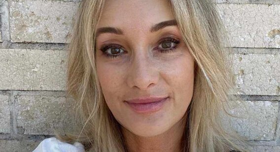 A headshot of a woman in front of a brick wall.