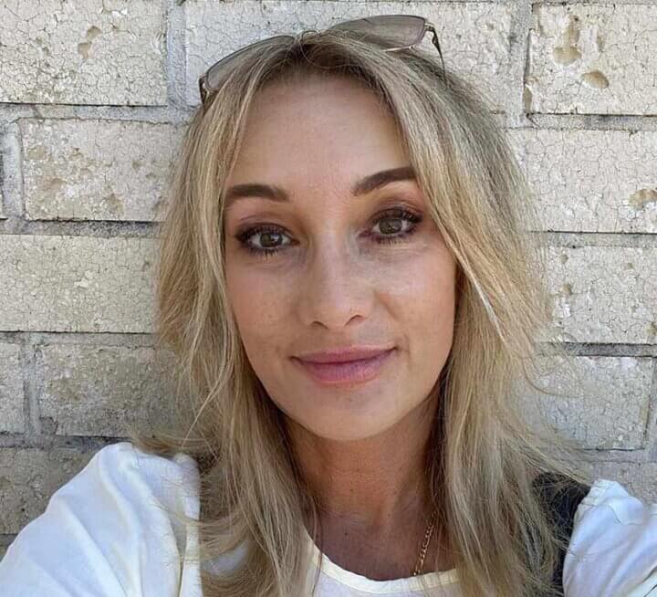 A headshot of a woman in front of a brick wall.