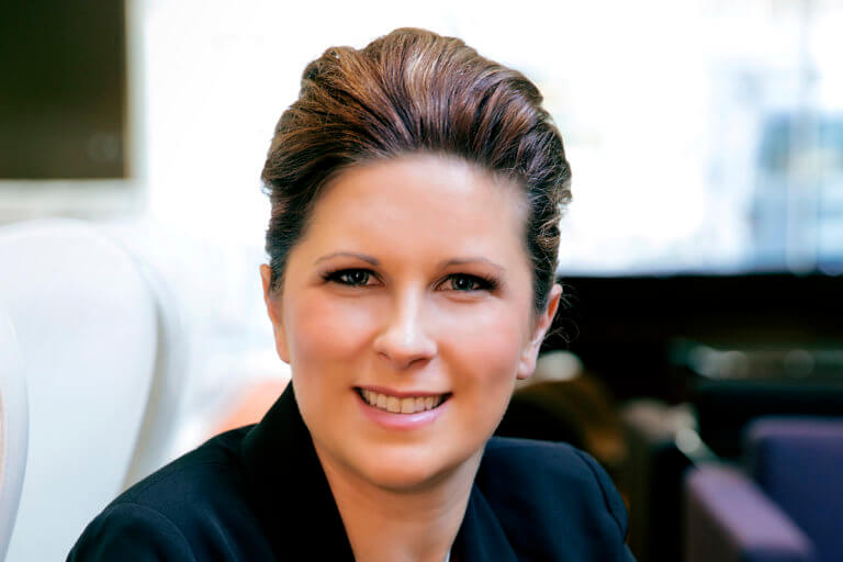 Woman in black jacket smiling facing front