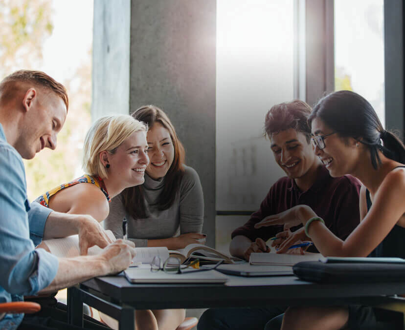 A group of five students studying psychology, sitting around a table with notebooks