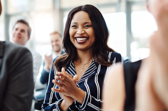 A female coaching student standing amongst her peers with her hands clasped together