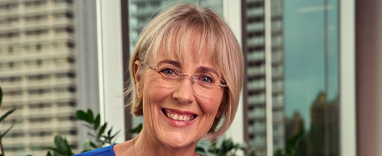 Monica looking at camera, with Sydney skyline behind her