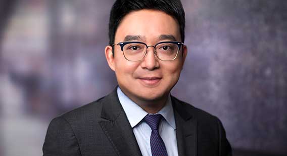 Portrait image of man in suit wearing glasses. Sean Dong