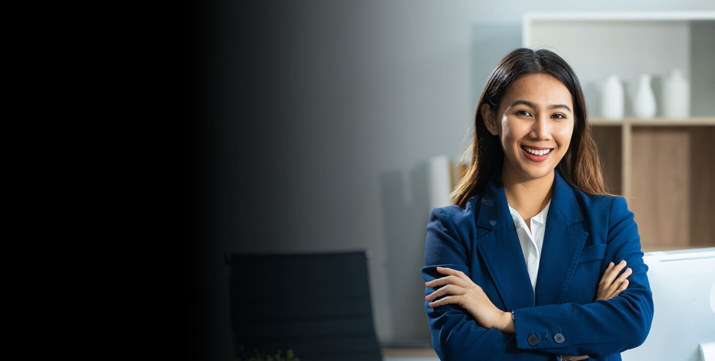A woman in a dark blue suit folding her arms and smiling towards camera - ACAP Graduate Diploma of Professional Accounting (2880x1188)