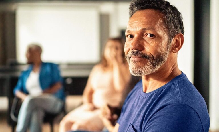 Man sitting in a counselling support group, facing towards camera