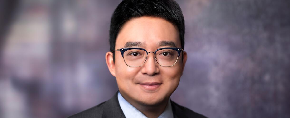 Portrait image of man in suit wearing glasses. Sean Dong