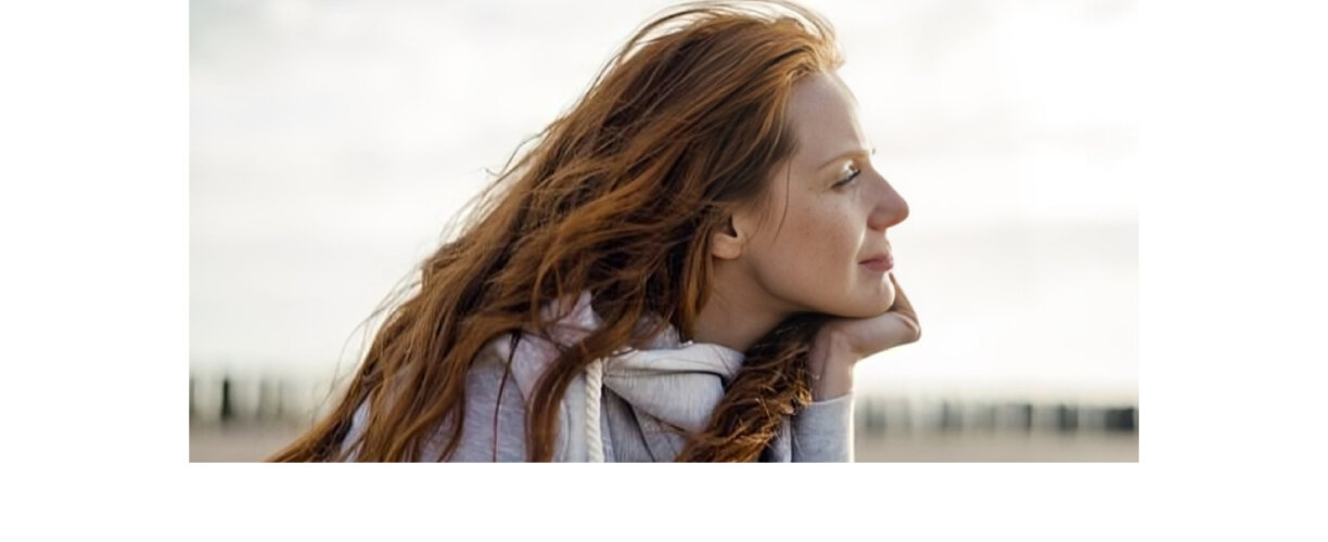 Person looking off in distance - hand on chin. Red haired woman