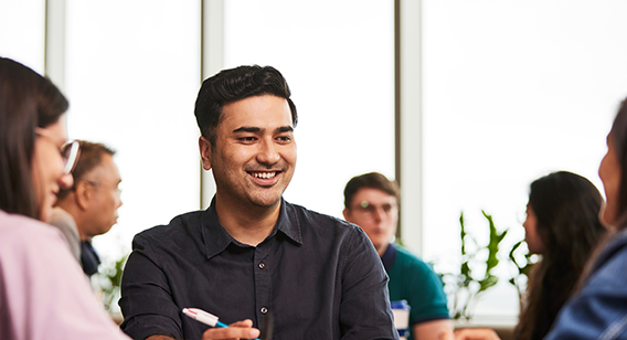 Rikesh, Master of Social Work (Qualifying) alumni working at a desk with two other ACAP students