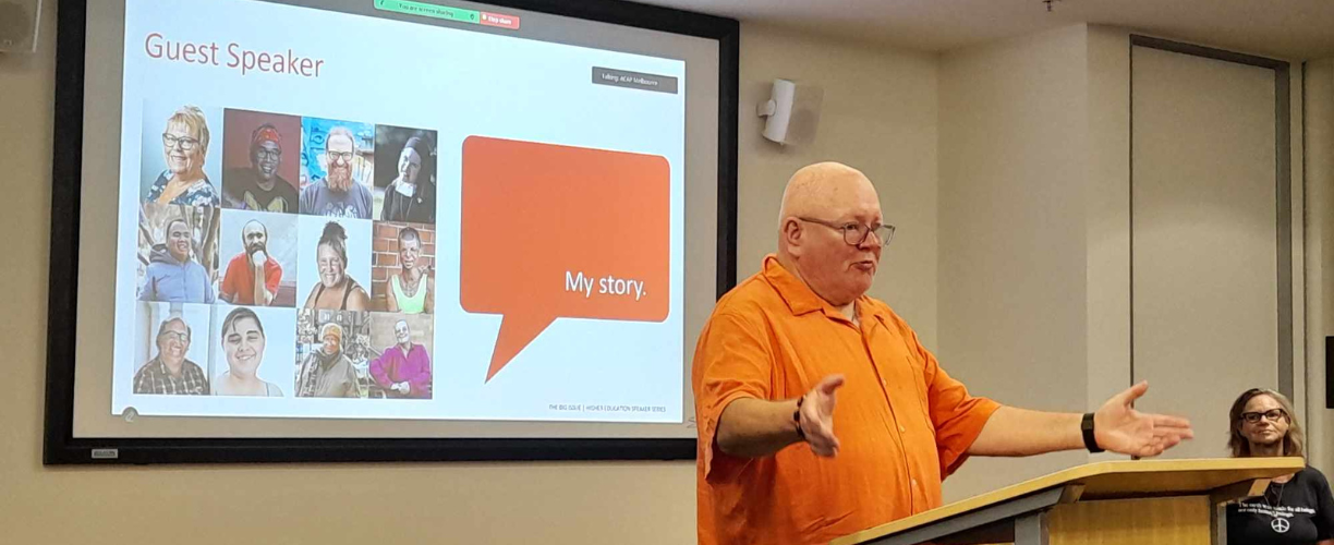 man in orange shirt presenting