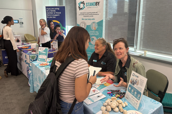 woman at trestle table expo stall speaks to another woman