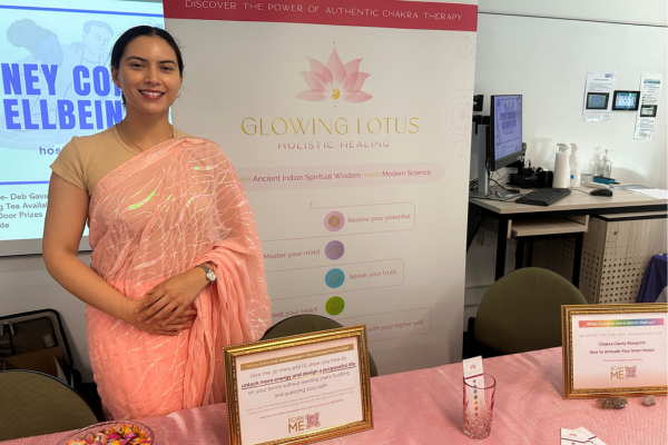 woman in pink sari in front of poster advertising chakra healing
