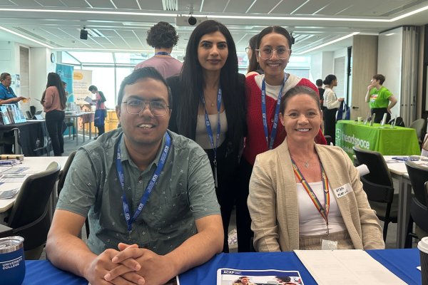 four people smile sitting at trestle table