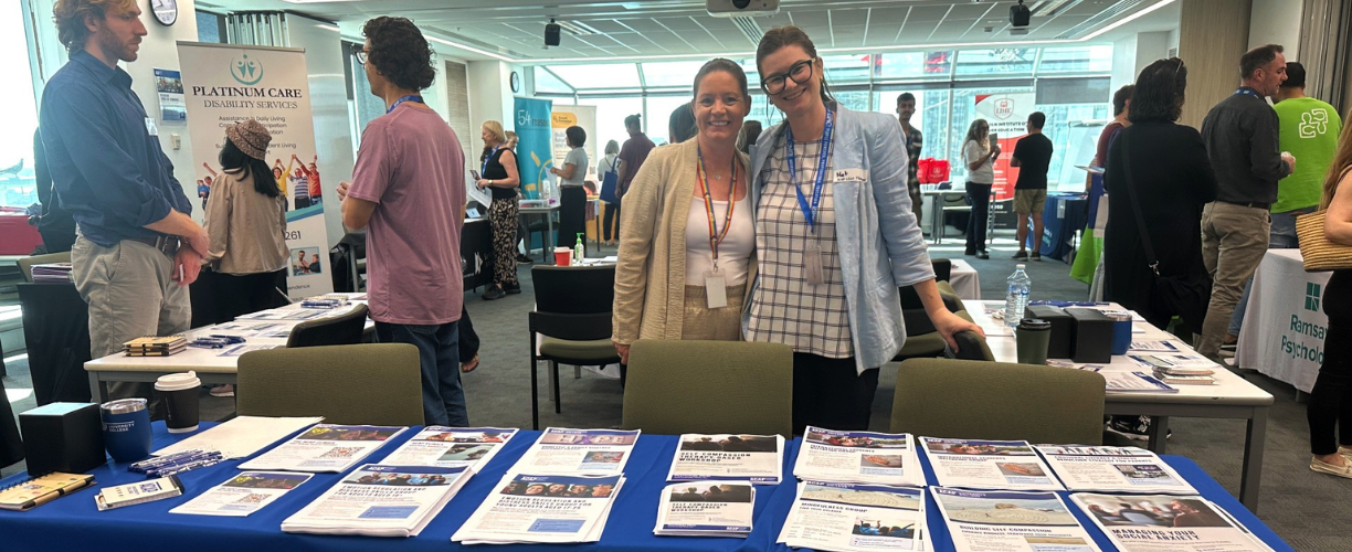 Two women behind table with brochures for ACAP Clinic on it